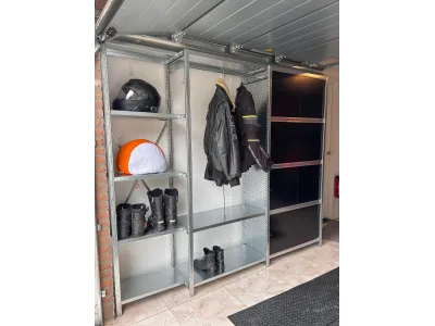 Stevige stellingkast met motoraccessoires en kleding, ideaal voor praktische garageopslag.