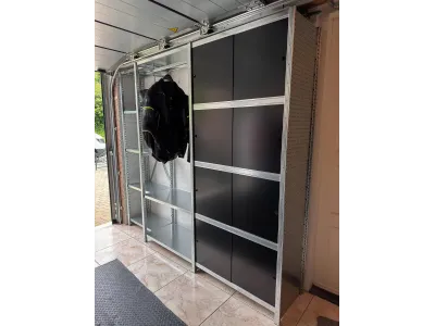Inloopkast met rij schuifdeuren boven elkaar en garderobe sectie toegepast in een garage.