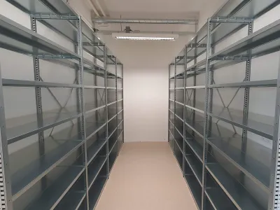 Metalen stellingkastdubbele rij in magazijnruimte langs de lange wanden geplaatst.