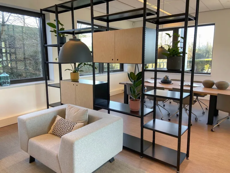 Roomdivider van zwarte stellingkast met houten draaideuren waardoor de ruimte optisch wordt gesplitst..