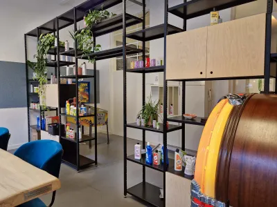 Zwart gecoate stellingkast als roomdivider met open legborden voor doorkijk en doorgang waar onderdoor gelopen kan worden.