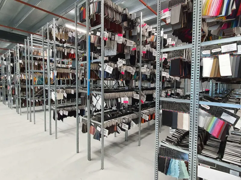 confectierekken in magazijn. Deze zijn ruggelings gemonteerd met smalle gangpaden voor optimale indeling.