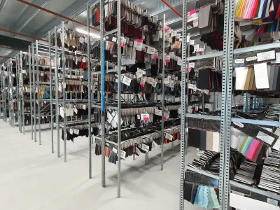 confectierekken in magazijn. Deze zijn ruggelings gemonteerd met smalle gangpaden voor optimale indeling.