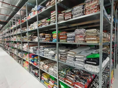 Confectiestelling in groot magazijn met veel open legborden voor opslag confectie stalen.