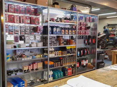 Metalen winkelstelling met schappen gevuld met producten in een georganiseerde werkplaats.