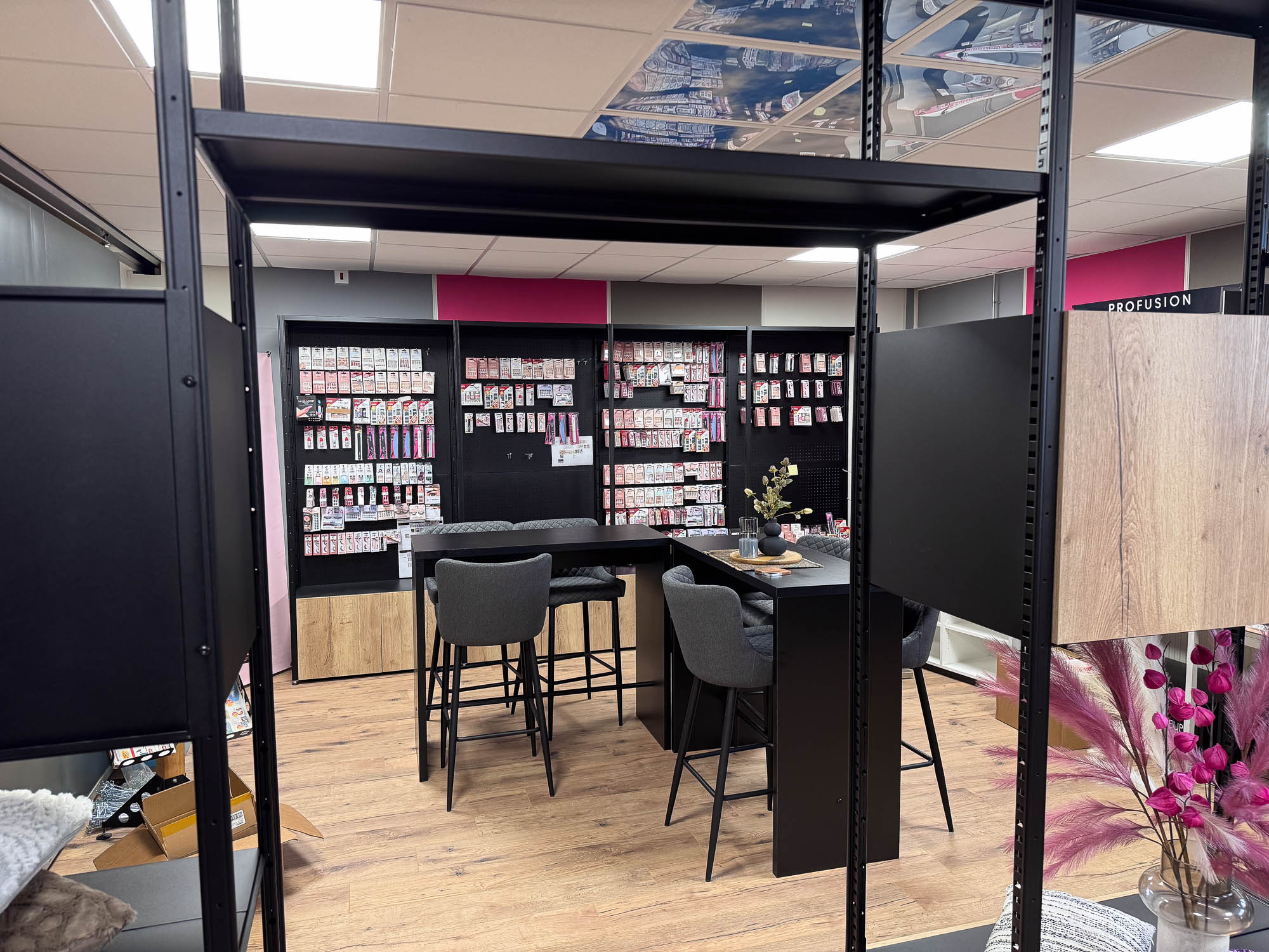 Achterzijde van roomdivider met zicht op showroom stellingkast met make-upproducten in het zwart uitgevoerd.