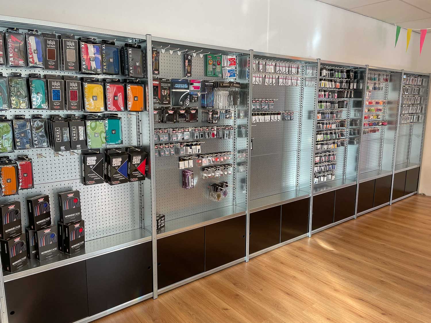 Geperforeerde stellingkasten met dartaccessoires en ophanghaken voor klein materiaal.