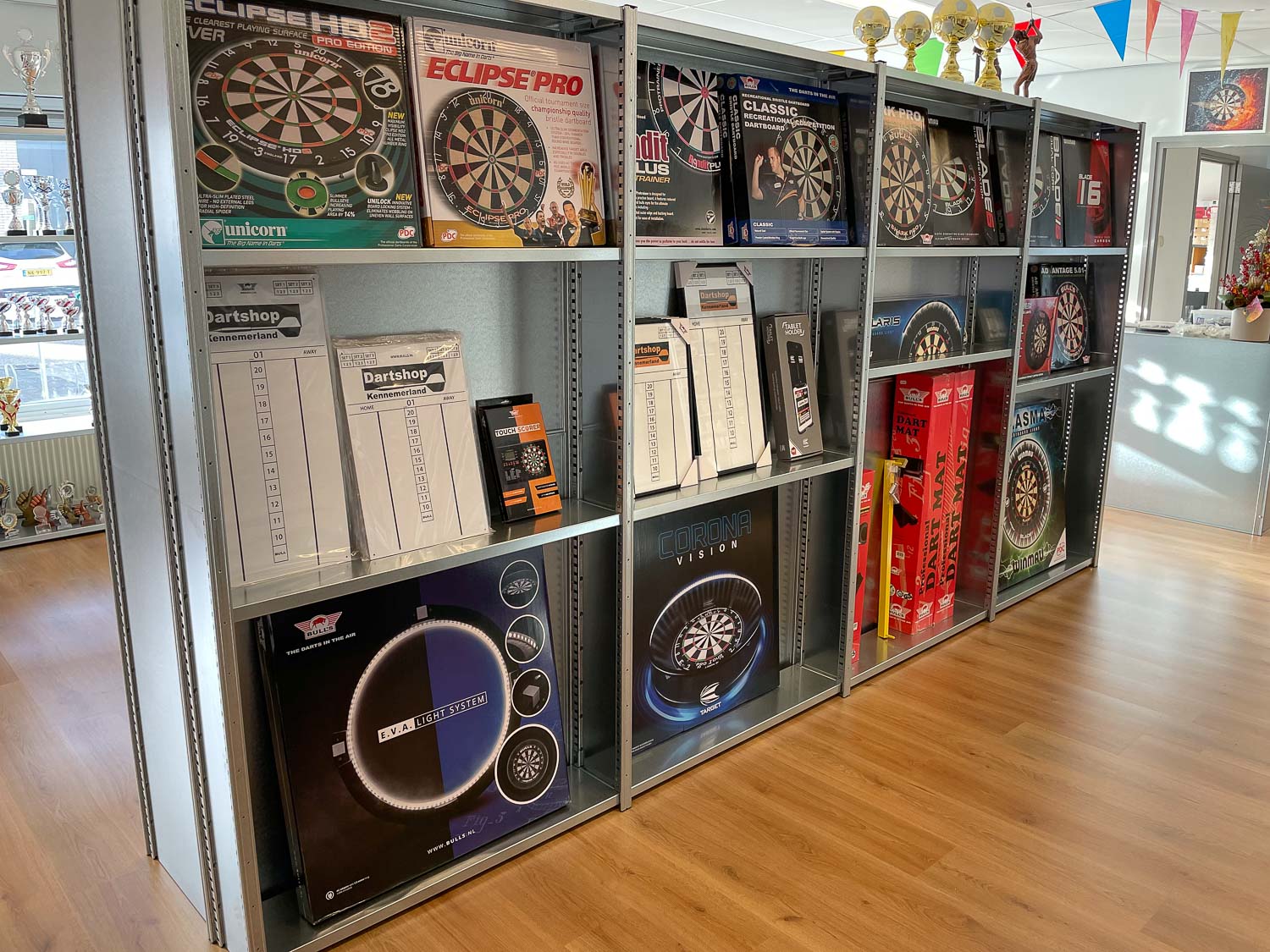 Stellingkasten als winkelmeubel met dartborden en displays in een nette winkelruimte.