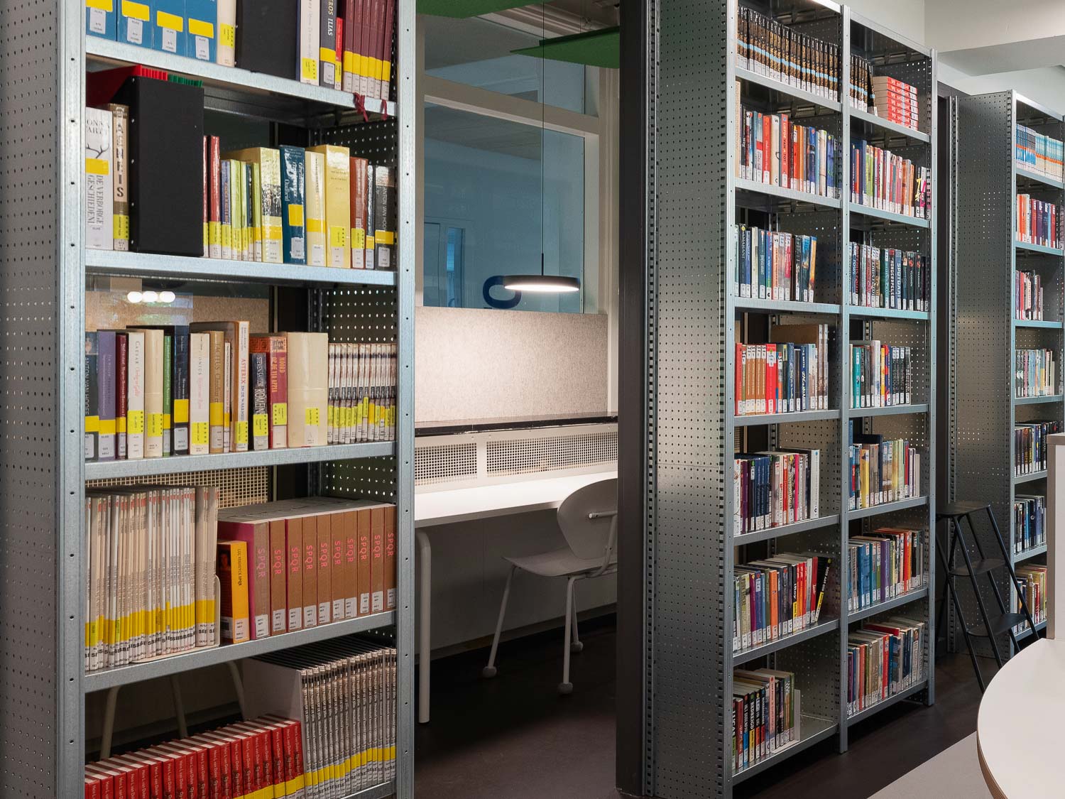 Industriële stellingkasten met boeken in mediatheek van Lyceum Sancta Maria in Haarlem
