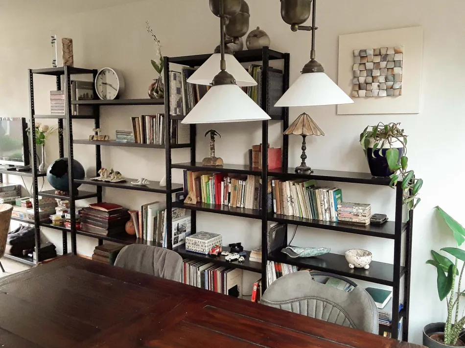 Open zwarte stellingkast met decoratie in een woonkamer.