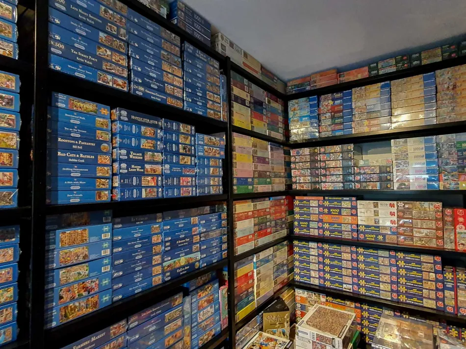 Zwarte stellingkast met legplanken vol met puzzels.